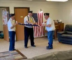 Three uniformed veterans folding the American flag