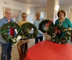 Senior citizens showing off Christmas wreaths they made