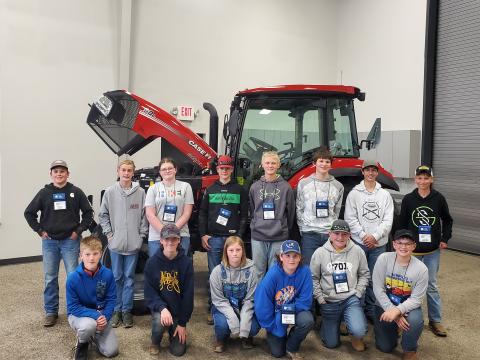 Past participants standing in front of a red tractor