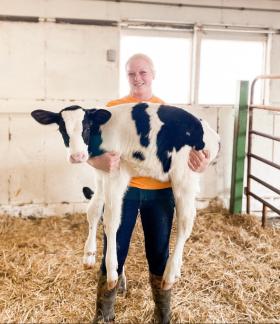 student holding a dairy cow in a pen