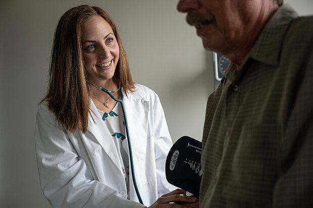 Photo of NDSU Nurse Practitioner graduate Natalie Carriveau interacting with a person in a clinical exam room