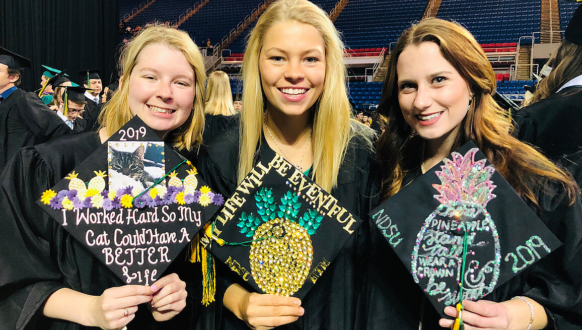 Photo of HTM students with decorated graduation caps