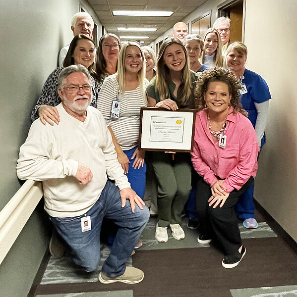 Photo of Essentia Health staff and patient Samantha Erickson with DNP Brooke Feltman holding framed award certificate.