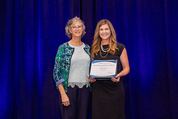 Photo of Dr. Allison Peltier accepting the AANP award for NP Award of Exellence at a national conference. 