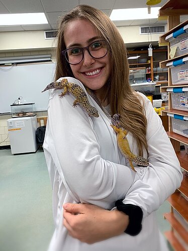 photo of undergraduate Elizabeth Rono posing with her study species, the Leopard Gecko.