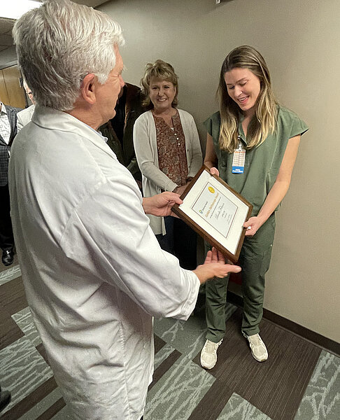 DNP and NDSU grad Brooke Feltman receives a framed certificate for a Golden Stethoscope award during a surprise informal ceremony