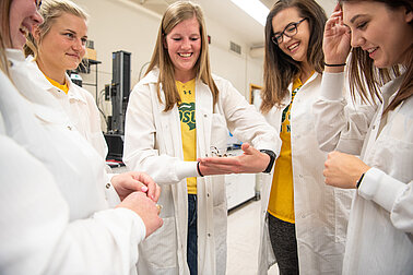 Image of women standing in lab coats in a group. Links to resources page.