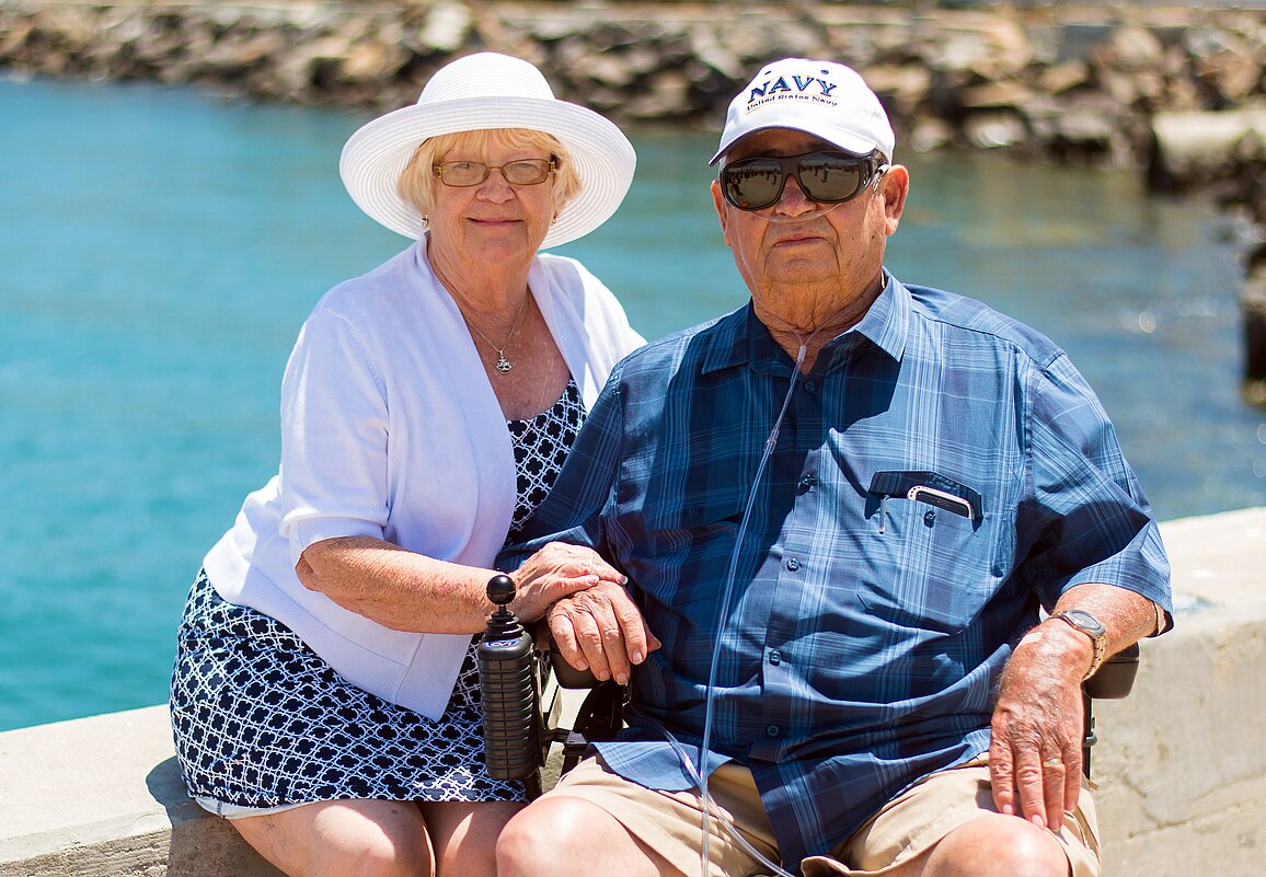 An elderly couple sitting near the water