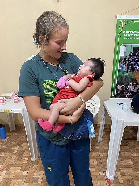 Photo of NDSU Nursing student cradling and smiling at a baby she is holding in Amazona, Brazil.