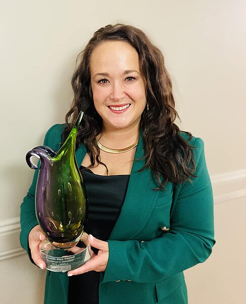 Photo of Dr. Elizabeth Skoy holding the ND Pharmacists Association Excellence in Innovation award of purple and green crystal glass award