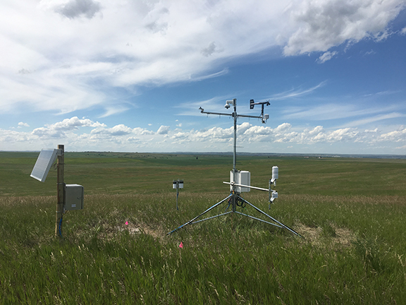 A remote weather station sitting in an open field.