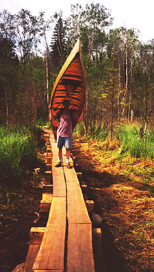 Photo of man carrying canoe.