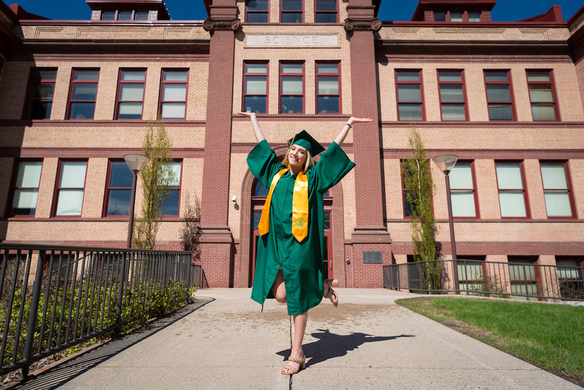 A student poses in front of campus academic building