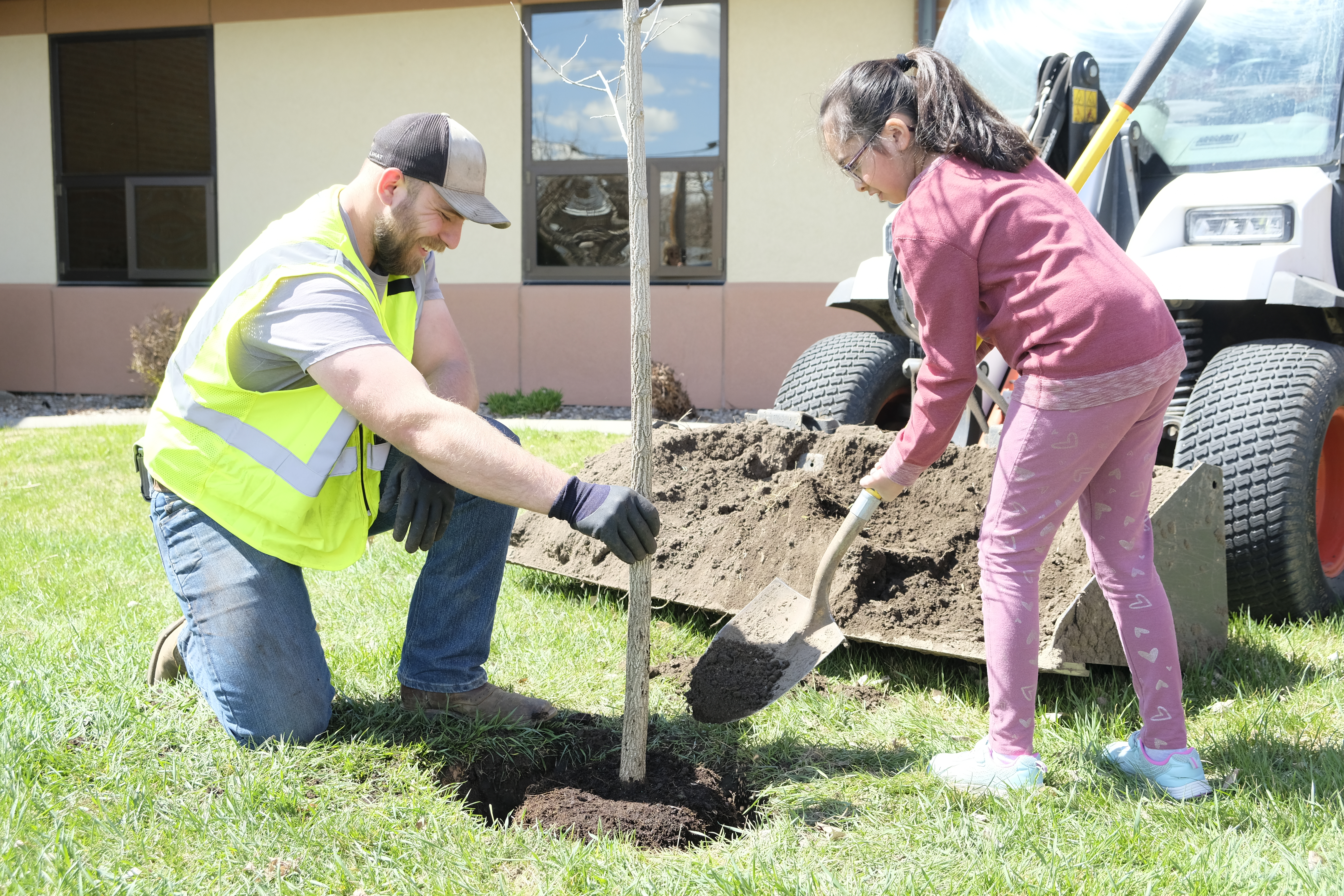 A man and a young girl plant a tree