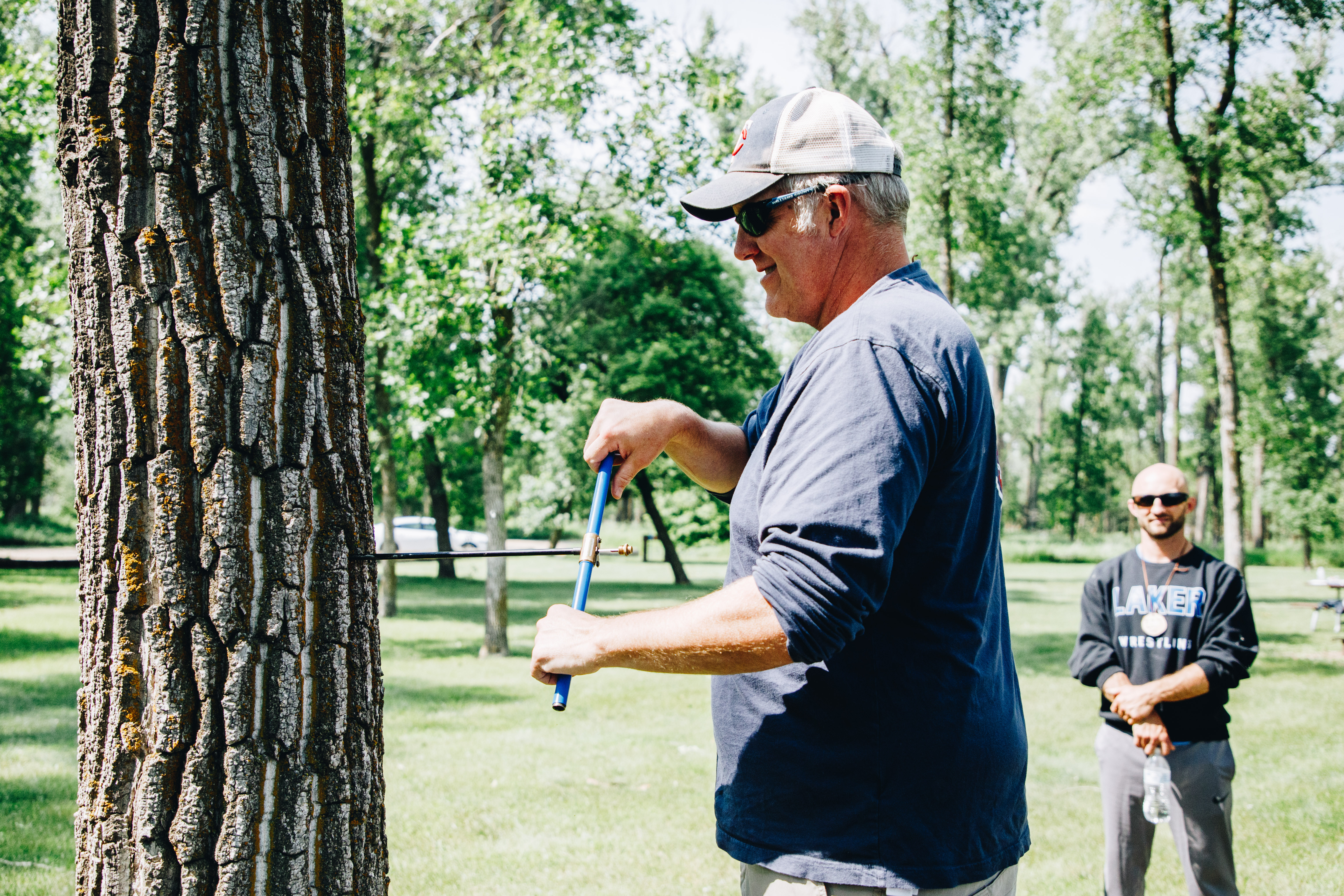 A man uses an increment borer to take a core sample from a tree