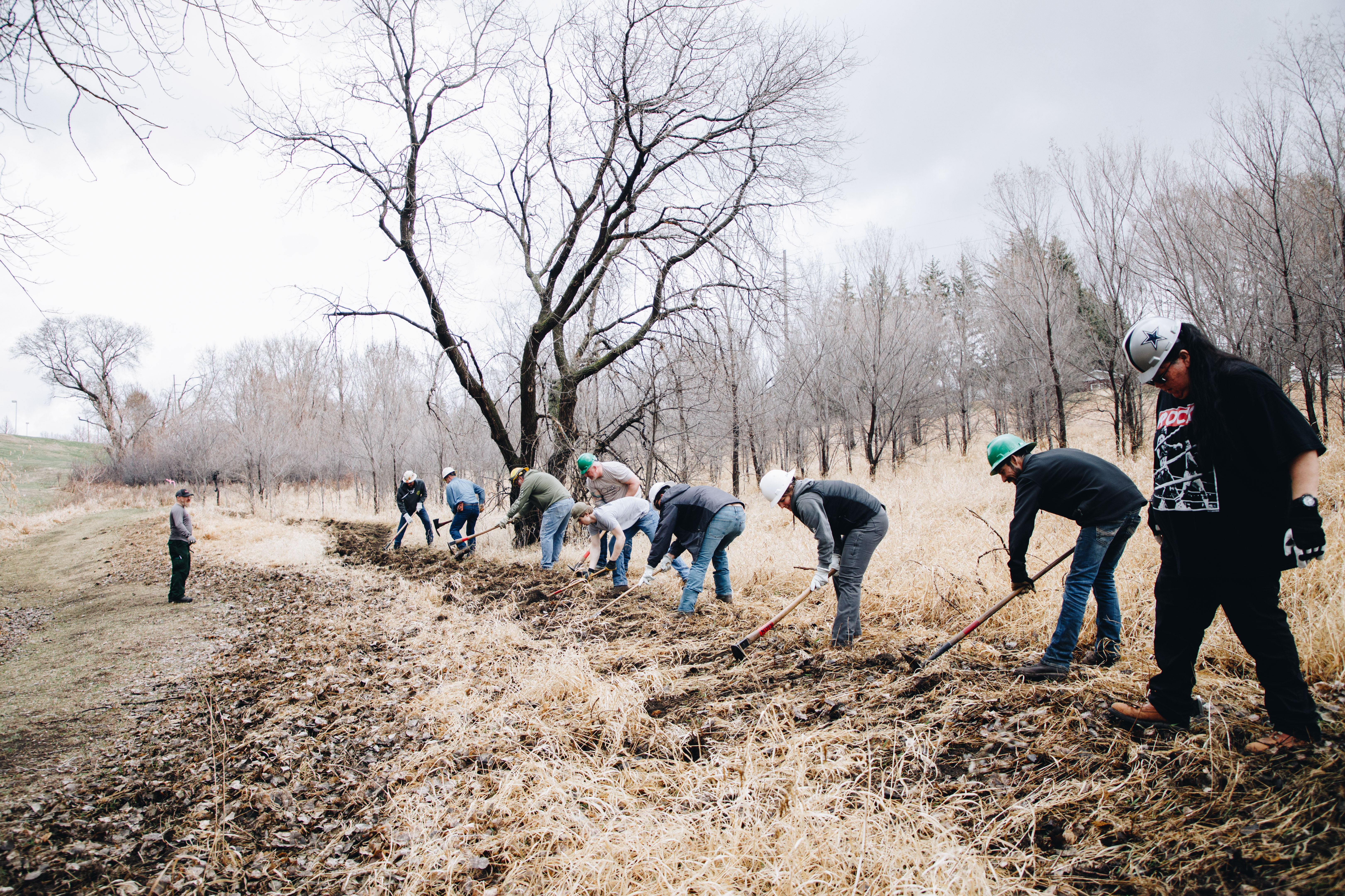 A group of firefighters dig a fire break in grass