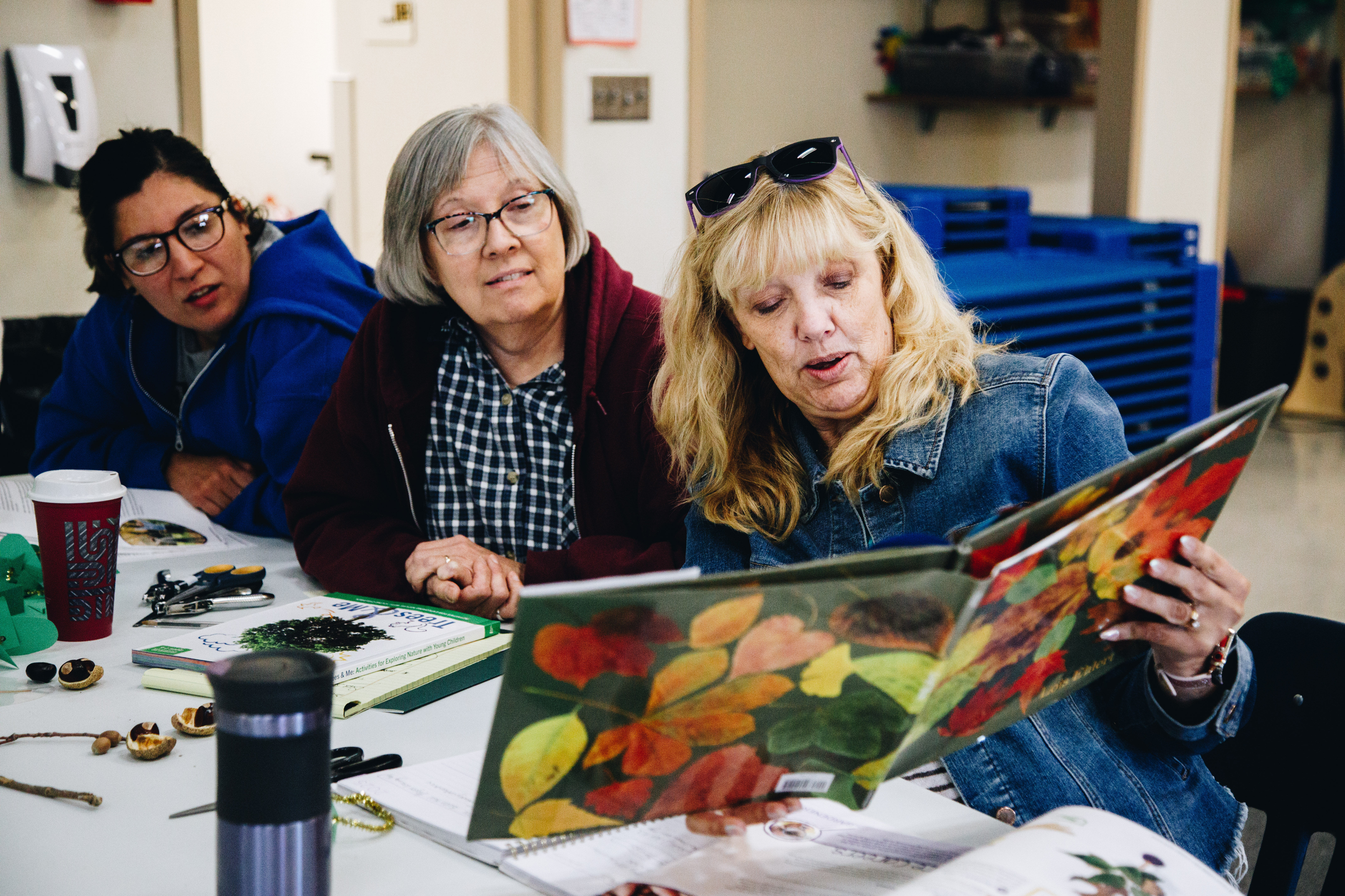 Three women read a book about leaves together
