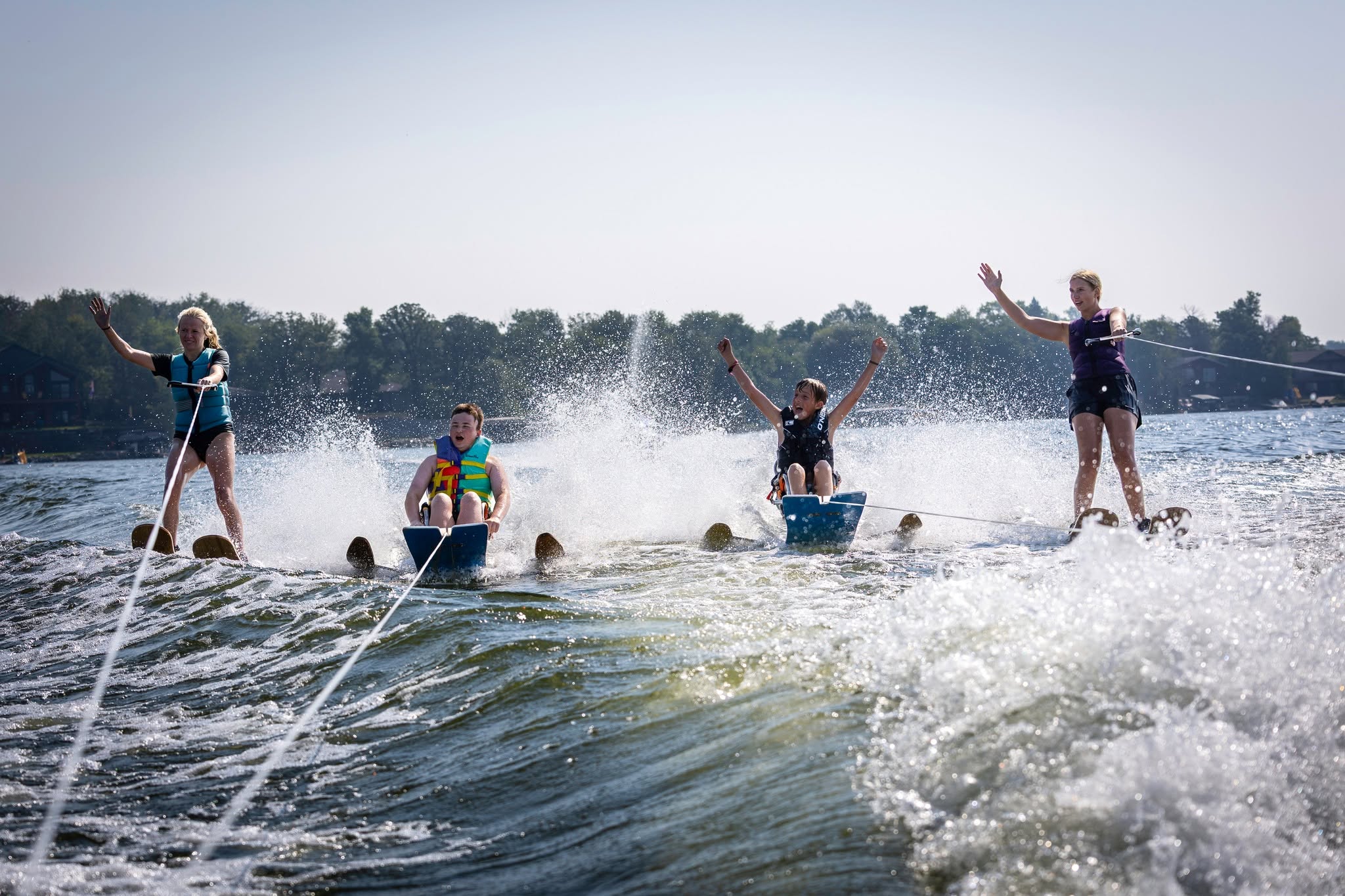 Four young people water ski, with two using adaptive technology.