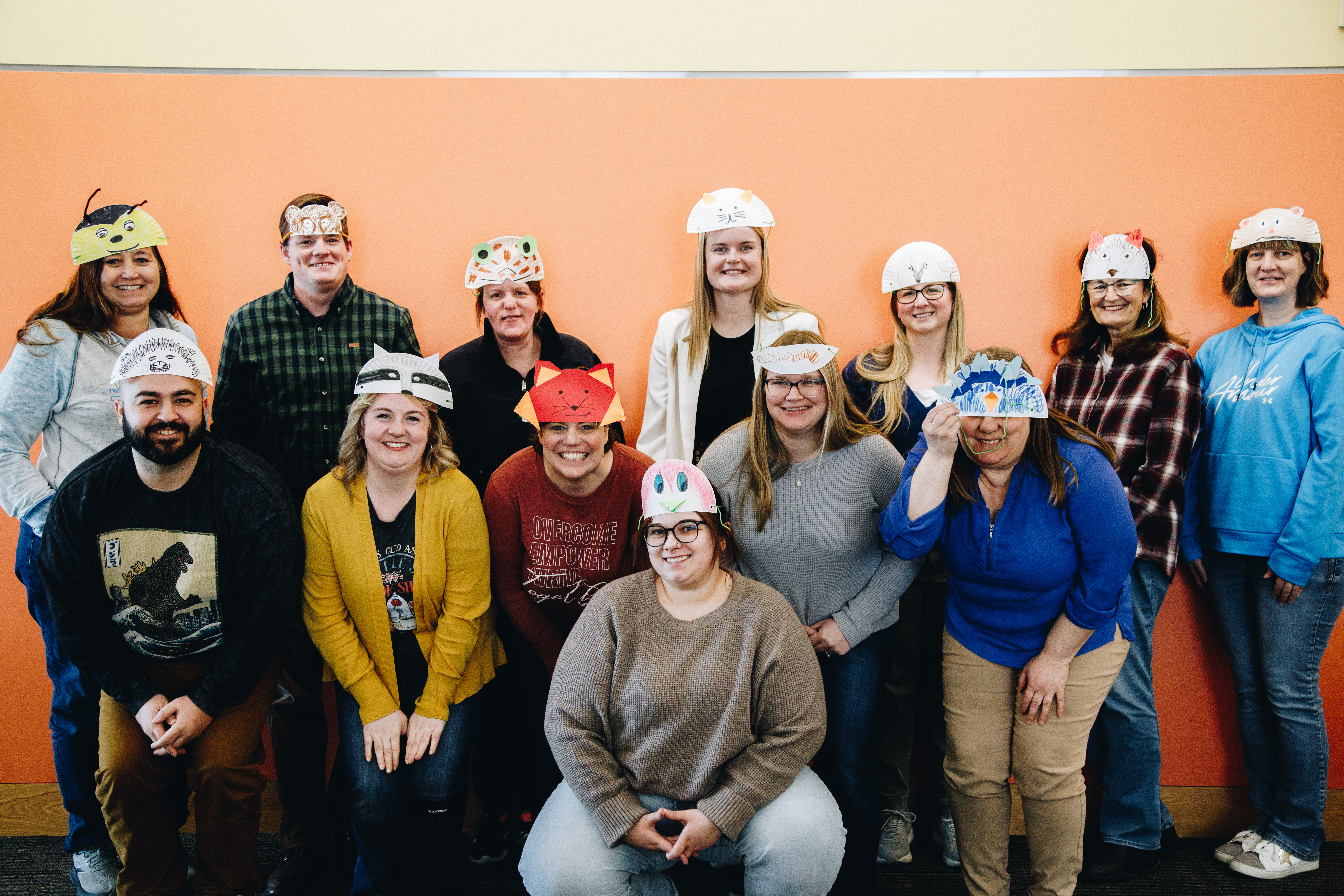A group of early childhood educators pose and smile wearing animal hats that they've made for creatures in the "Goodnight Owl" book