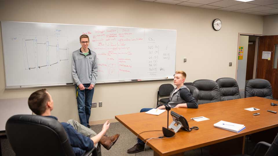 three ndsu students talking by whiteboard