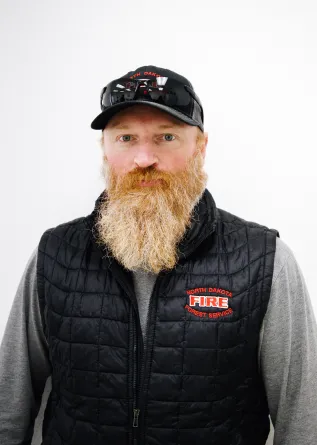 A man with a long red beard and sunglasses on top of his head with a baseball cap