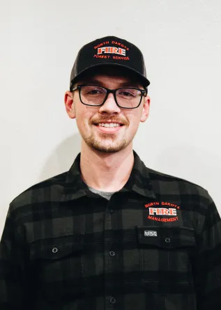 A man with glasses and a baseball cap smiling
