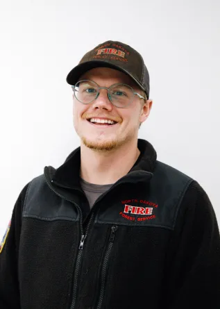 A man with glasses and a baseball cap smiling