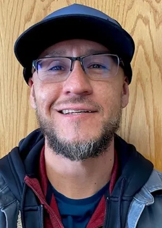 A man with glasses and a ball cap smiles