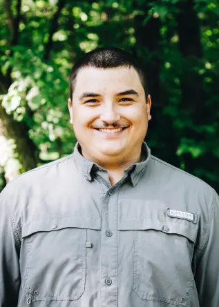 A Man smiling with trees in the background