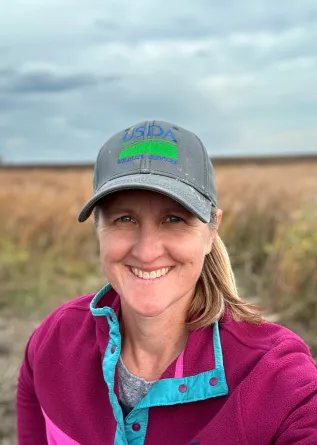Klug wearing a baseball cap while smiling confidently at camera.