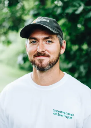 A man with a baseball cap grins