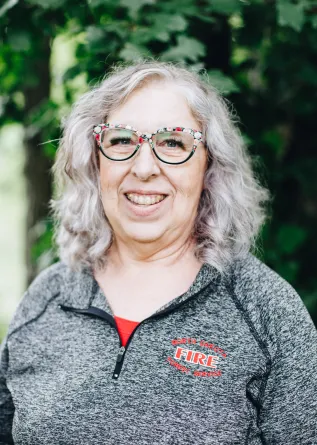 A woman with glasses smiles