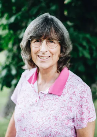 A woman with glasses smiles