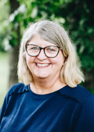 A woman with glasses smiles