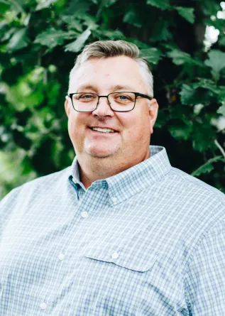 A man with glasses smiling