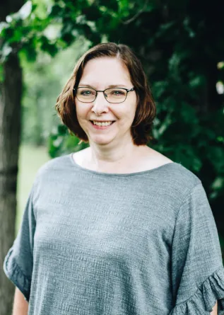 A woman with glasses smiles