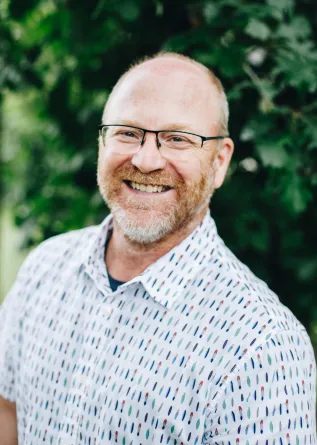 A man with glasses and a beard smiles