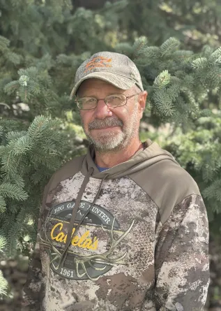 A man in a ballcap and glasses grinning