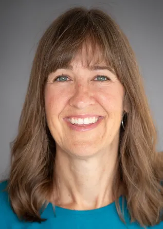 Britt Heidinger wearing a teal colored shirt in front of a gray background.