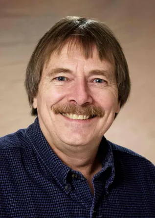 Dennis Tallman smiling confidently at the camera.
