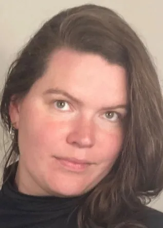 A headshot of RoseE Hadden a white woman with brown hair in her mid-30s.