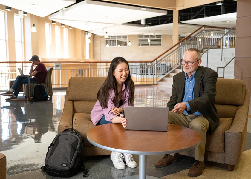 Student showing laptop to instructor in Barry Hall study area.