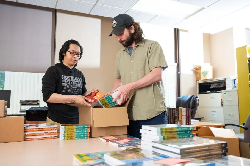 two students boxing up books