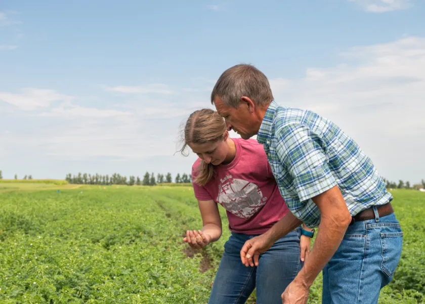 student working with a professor in a field