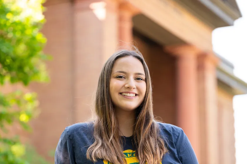 Student sitting in front of campus building
