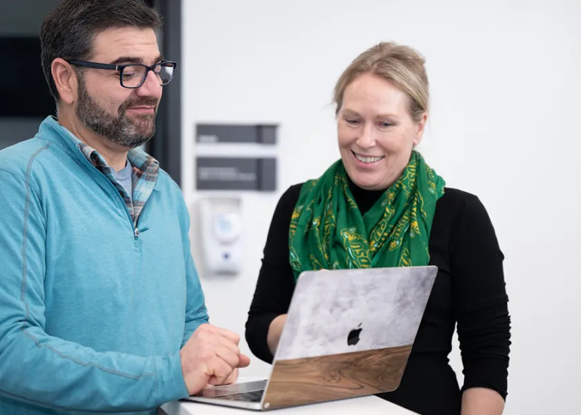 student and professor looking at an assignment on a laptop