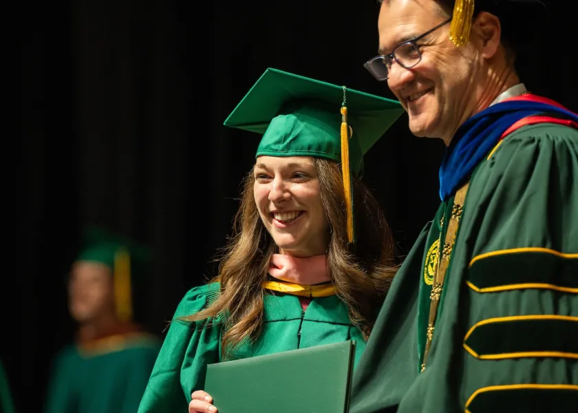 Photo of a student and President David Cook at spring commencement