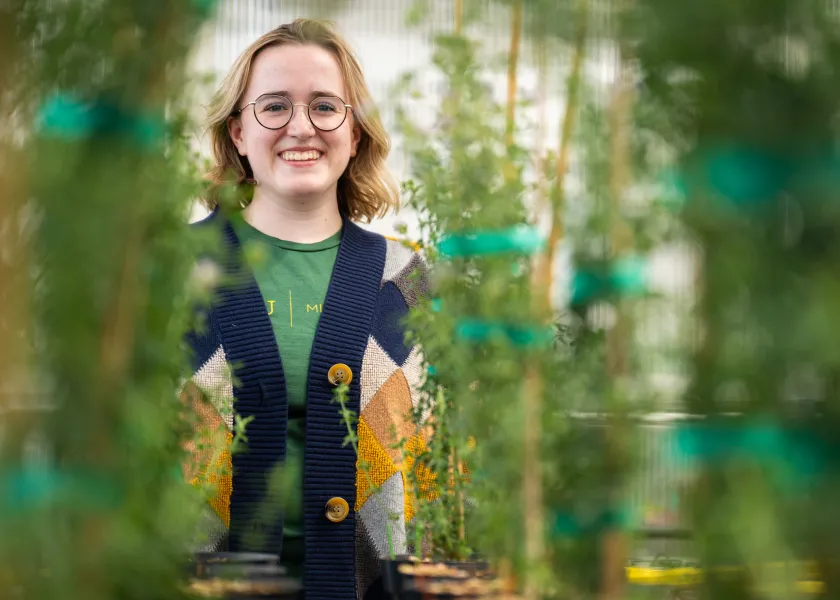 Microbiology's Marley Lund-Peterson holds up a pair of plants.