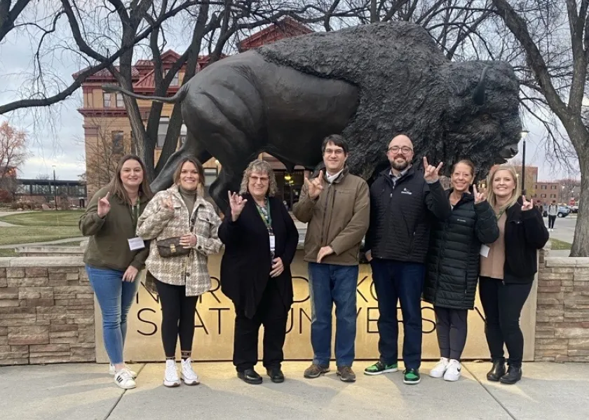 A group of high school counselors by the Bison statue