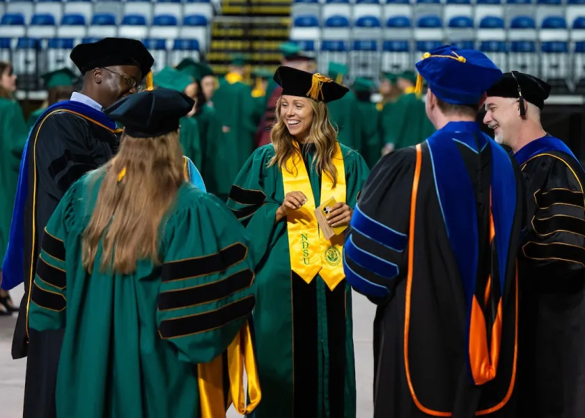 students and faculty talking before NDSU's commencement ceremony